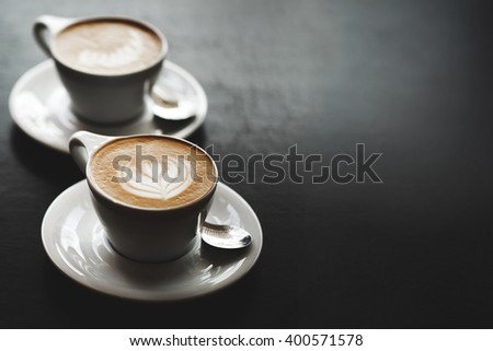 Two cups of cappuccino with latte art on black table. Morning coffee for couple in love. Top view.