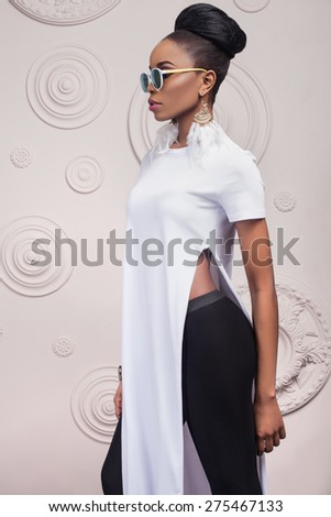 A beautiful dark-skinned woman in a long white dress with a deep cut and black Legency .