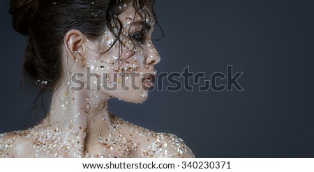 Beauty portrait of a young beautiful girl , shot in profile Europeans . Clean wet pearl leather covered with small seashells, dark hair gathered in a ponytail