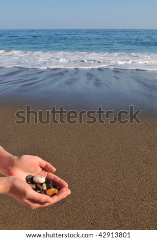 Stones in female hands against the sea