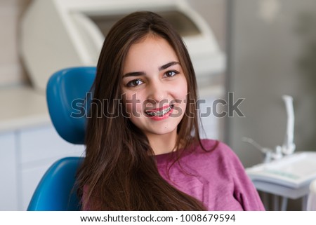 Beautiful girl with braces smiles in dentistry.
