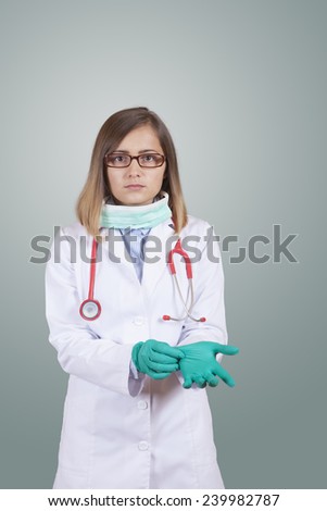 Beautiful young doctor (or nurse) wearing mask and red stethoscope take up latex gloves