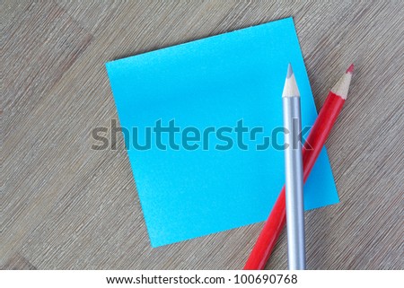 Blank blue post-it note with colorful pencils