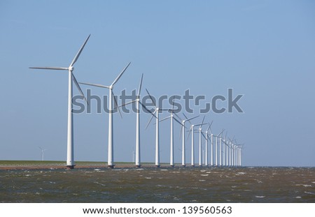 Row of Wind turbines in the ocean with a clear blue sky