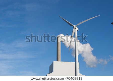 alternative energy wind turbines by the two smoking pipes of the factory