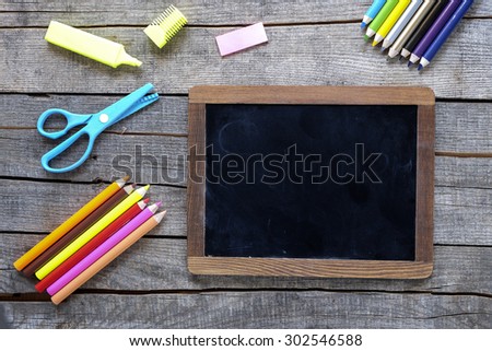 Colored pencils and writing board on wood