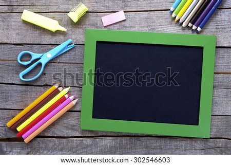 Colored pencils and writing board on wood