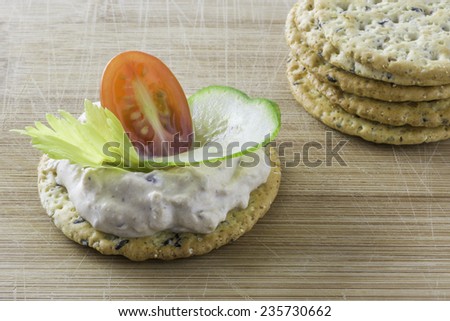 Tuna Cheese Spread on grain cracker, hors d\'oeuvre, decorated with celery, tomato and cucumber.