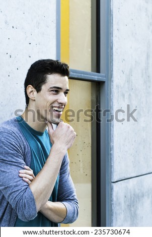 Candid portrait of a young beautiful man smiling in modern urban area with copy space.