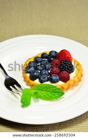 Summer berry tart served with a touch of mint