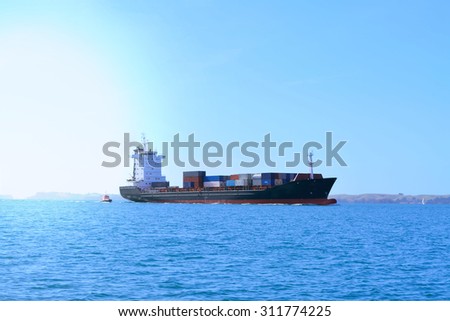 Container cargo ship accompanied by a pilot boat in still water of Auckland harbour