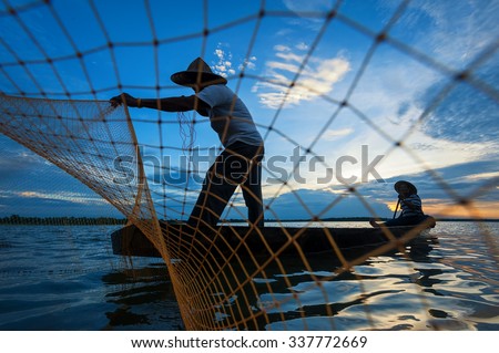 Fisherman of lake in action when fishing on twilight,Thailand