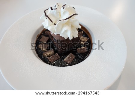 Chocolate fudge cake and ice cream on chocolate sauce and wafer with whip cream on top