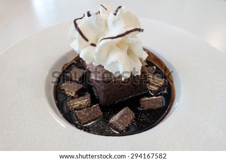 Chocolate fudge cake and ice cream on chocolate sauce and wafer with whip cream on top