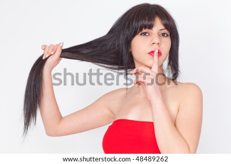 attractive young woman posing in studio on white background, holding her long black hair with one hand, finger on red lips