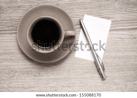 Toned image, cup of black coffee, pen and blank sheet of paper on wooden table