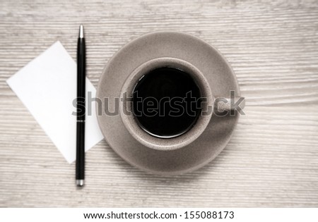 Toned image, cup of black coffee, pen and blank sheet of paper on wooden table