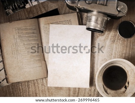 Artwork in retro style, old-fashioned camera, opened book, empty cup of coffee