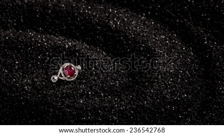 Ruby ring on a black sand background