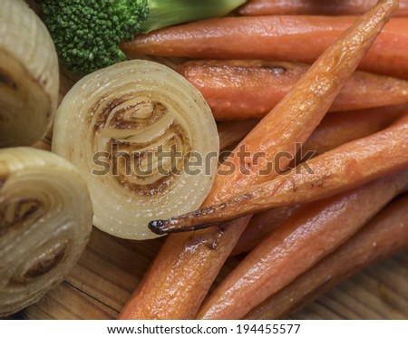 Perfectly roasted carrots and onions on a wooden platter