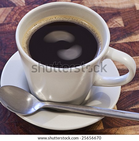 A cup of coffee sitting on a saucer with interesting swirls in liquid.