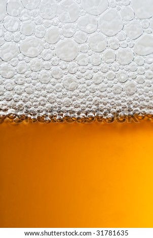 A close up of a glass of beer with lovely amber colour and white frothy bubbles on top.