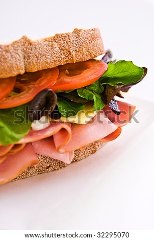 A gourmet sandwich of ham, cheese, lettuce, tomato and mayonnaise isolated on white.