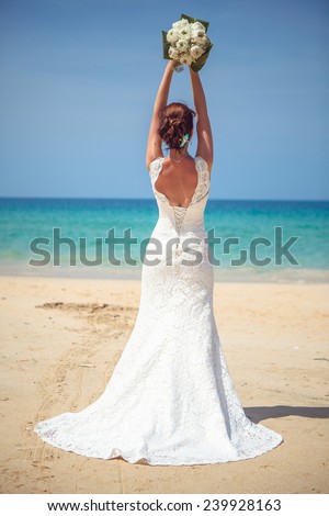 happy girl in a wedding dress with a bouquet by the sea