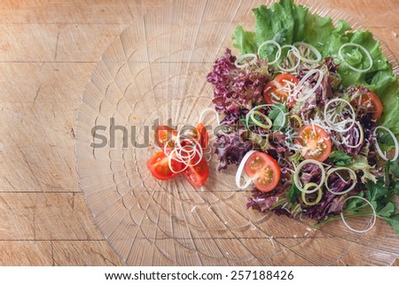 vegetable salad in a glass dish on a wooden cutting board with space for writing