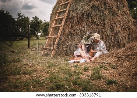 loving man and woman in a linen dress on a background of haystacks with  homemade bread