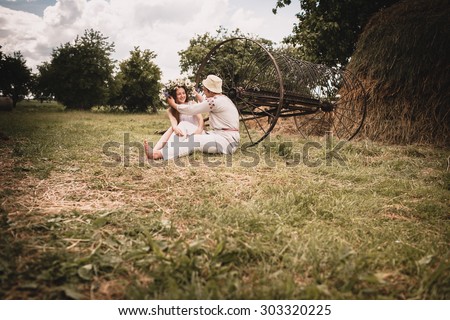couple clothed in linen near haystacks in village
