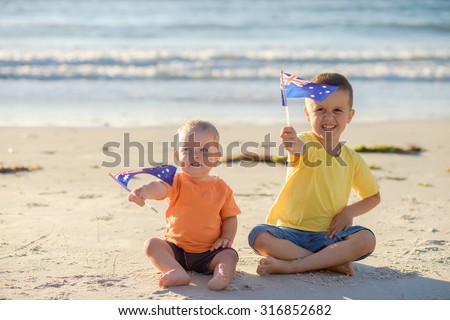 Smiling kids with flags of Australia at the beach
