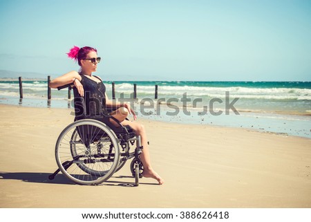 Disabled woman in the wheelchair at the beach. Cross-processed and color-toned image.