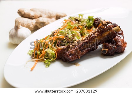 Lamb ribs with sweet sauce with salad dressing on a white plate