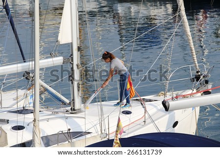 BARCELONA, SPAIN - SEPTEMBER 25, 2014: Spanish woman washes a yacht moored in Puerto Olimpico in Barcelona