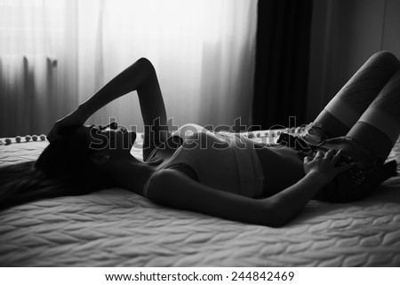 beautiful exiting slim woman lying in the bed in the dark