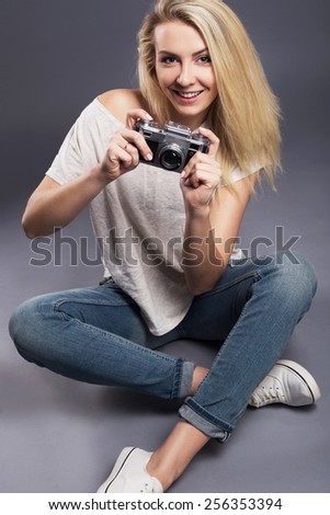 beautiful sporty smiling girl photographer using old camera in studio against grey background