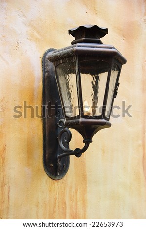 Old-fashioned metal lamp on colorful stucco wall