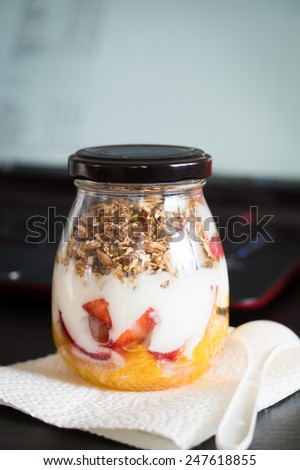 Granola with Oranges, Strawberries and Plain Yogurt in a Jar as a Snack to Take to Work