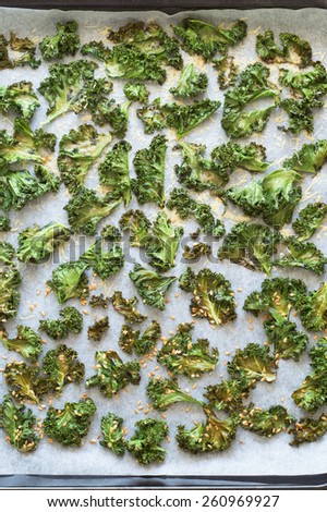 Freshly Baked Curly Kale Chips Sprinkled with Parmesan Cheese and Flax Seeds on the Baking Sheet