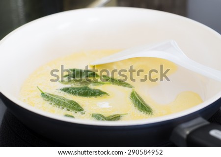 Closeup of Fresh Sage Leaves Being Fried with Butter in a Ceramic Pan