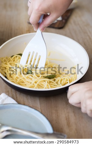Hands Mixing Spaghetti with Melted Butter and Fried Sage Leaves in a Ceramic Pan