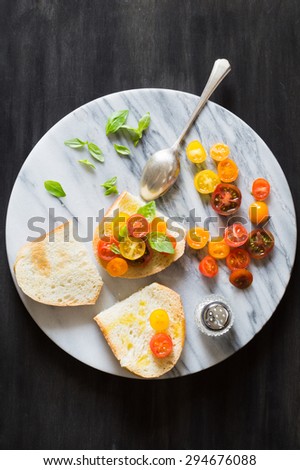 Bruschetta with a Mix of Red, Orange and Yellow Cherry Tomatoes and Basil Leaves