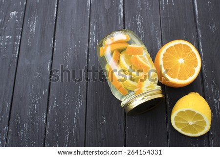 Jar of tasty fresh lemonade with lemon and orange in wooden black background