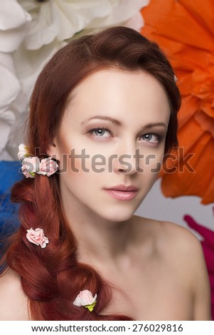 Close up beautiful women portrait with red hair, beauty make up with long hair braided in a braid and small roses there and big colorful flowers on background
