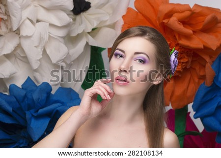 Beauty women portrait holding hair near face and big colorful flowers on background