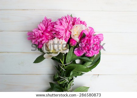Many beautiful colored peonies on vintage wooden background