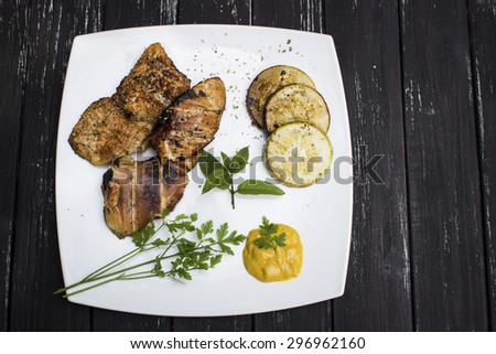 Grilled steaks, baked squash on dark wooden background