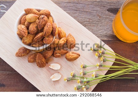 Almond paste in a cup on a wooden cutting board with orange flowers and props.