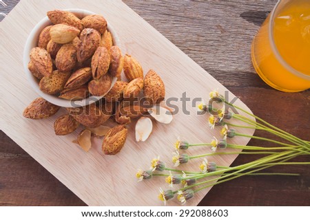 Almond paste in a cup on a wooden cutting board with orange flowers and props.